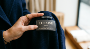 A high-end editorial close-up of a stylish person’s hand delicately holding a high-quality fabric la