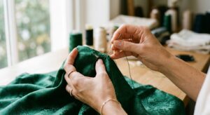 A sophisticated, editorial-style close-up of a pair of elegant hands meticulously mending a piece of